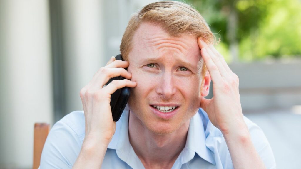 Homme perturbé tenant son téléphone à l'oreille avec une expression préoccupée.