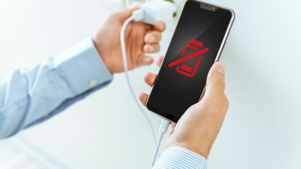 Homme branchant le chargeur d'un smartphone affichant une icône de batterie rouge 