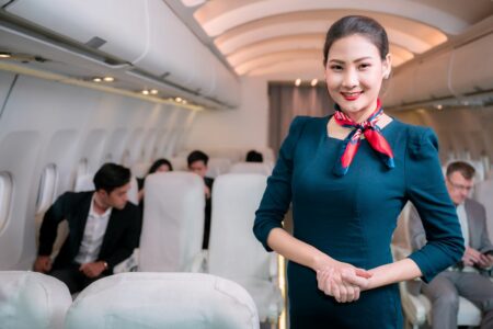 Une hôtesse de l'air souriante dans un avion avec des passagers.